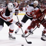 New Jersey Devils' Damon Severson (28) controls the puck in front of Arizona Coyotes' Craig Cunningham (22) and Devils' Michael Ryder, back, during the second period of an NHL hockey game Saturday, March 14, 2015, in Glendale, Ariz. (AP Photo/Ross D. Franklin)
