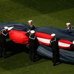 Members of the military unfurl a large American flag on the field before a baseball game between the Washington Nationals and the New York Mets on opening day at at Nationals Park, Monday, April 6, 2015, in Washington. (AP Photo/Andrew Harnik)