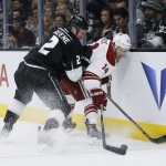 Los Angeles Kings defenseman Matt Greene, left, checks Arizona Coyotes center Joe Vitale, right, into the boards as he reaches for the puck during the first period of an NHL hockey game, Monday, March 16, 2015, in Los Angeles. (AP Photo/Danny Moloshok)