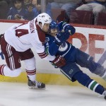 Vancouver Canucks defenseman Chris Tanev (8) goes into the boards with Arizona Coyotes right wing B.J. Crombeen (44) during the third period of an NHL hockey game Thursday, April 9, 2015, in Vancouver, British Columbia. (AP Photo/The Canadian Press, Jonathan Hayward)