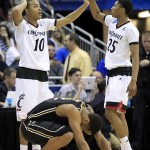 Cincinnati guard Troy Caupain, left, congratulates teammate Kevin Johnson after Purdue forward Vince Edwards, bottom, missed a last-second shot during overtime of an NCAA tournament second round college basketball game in Louisville, Ky., Thursday, March 19, 2015. Cincinnati won 66-65. (AP Photo/David Stephenson)