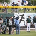 Actor Will Ferrell, second from right, warms up for the Oakland Athletics prior to the first inning of a spring training baseball game against the Seattle Mariners, Thursday, March 12, 2015, in Mesa, Ariz. Telling everyone "I'm a five-tool guy," Will Ferrell was off on his barnstorming tour Thursday through five Arizona spring training games. (AP Photo/Matt York)