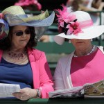 Fans read a program before the 141th running of the Kentucky Oaks horse race at Churchill Downs Friday, May 1, 2015, in Louisville, Ky. (AP Photo/Jeff Roberson)