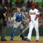 The Diamondbacks' Didi Gregorius, right, walks away after he was called out by umpire Tim Welke, left, and the Dodgers' catcher A.J. Ellis exchange balls during the Major League Baseball opening game between the Los Angeles Dodgers and Arizona Diamondbacks at the Sydney Cricket ground in Sydney, Saturday, March 22, 2014. (AP Photo/Rick Rycroft)