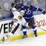 Chicago Blackhawks center Andrew Shaw (65) falls to the ice after being checked by Tampa Bay Lightning defenseman Jason Garrison (5) during the second period of Game 5 of the NHL hockey Stanley Cup Final, Saturday, June 13, 2015, in Tampa, Fla. (AP Photo/John Raoux)
