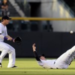 Colorado Rockies left fielder Corey Dickerson, left, runs up as Rockies shortstop Josh Rutledge falls to the ground while trying to reach a fly ball by Arizona Diamondbacks' Miguel Montero in the first inning of a baseball game Friday, Sept. 19, 2014, in Denver. (AP Photo/Chris Schneider)