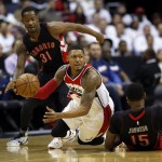 Washington Wizards guard Bradley Beal (3) passes the ball as he falls between Toronto Raptors forwards Terrence Ross (31) and Amir Johnson (15) during the first half of Game 3 in the first round of the NBA basketball playoffs Friday, April 24, 2015, in Washington. (AP Photo/Alex Brandon)
