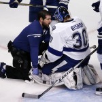 Tampa Bay Lightning goalie Ben Bishop is checked on by a trainer after being knocked down by Chicago Blackhawks' Brandon Saad during the second period in Game 3 of the NHL hockey Stanley Cup Final on Monday, June 8, 2015, in Chicago. (AP Photo/Charles Rex Arbogast)