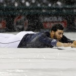 Cleveland Indians' Mike Aviles slides on the tarp after the baseball game between the Indians the Arizona Diamondbacks was postponed Tuesday, Aug. 12, 2014, in Cleveland. (AP Photo/Tony Dejak)