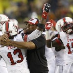 Utah linebacker Gionni Paul (13) is hugged by Assistant Head Coach Kalani Fifita Sitake on the sidelines after he intercepted a pass from Michigan quarterback Devin Gardner during the second half of an NCAA college football game in Ann Arbor, Mich., Saturday, Sept. 20, 2014. (AP Photo/Carlos Osorio)
