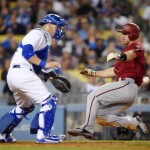 Arizona Diamondbacks' Paul Goldschmidt, right, scores on a sacrifice fly by Chris Owings as Los Angeles Dodgers catcher Yasmani Grandal waits for the throw during the seventh inning of a baseball game, Wednesday, June 10, 2015, in Los Angeles. (AP Photo/Mark J. Terrill)