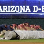 The grounds crew pulls the tarp during a rain delay in a baseball game between the Cleveland Indians and the Arizona Diamondbacks, Tuesday, Aug. 12, 2014, in Cleveland. The game was postponed. (AP Photo/Tony Dejak)
