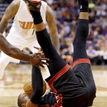 Miami Heat's Dwyane Wade falls down after having his shot blocked by Phoenix Suns' Miles Plumlee sent him to the floor during the first half of an NBA basketball game Tuesday, Dec. 9, 2014, in Phoenix. (AP Photo/Ross D. Franklin)