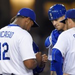 Los Angeles Dodgers catcher Yasmani Grandal, center, and first baseman Adrian Gonzalez, right, looks at relief pitcher Juan Nicasio's hand before he was taken out of the game during the sixth inning of a baseball game against the Arizona Diamondbacks, Wednesday, June 10, 2015, in Los Angeles. (AP Photo/Mark J. Terrill)