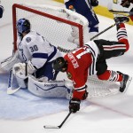 Chicago Blackhawks' Andrew Desjardins, right, falls as Tampa Bay Lightning goalie Ben Bishop looks for the puck during the second period in Game 6 of the NHL hockey Stanley Cup Final series on Monday, June 15, 2015, in Chicago. (AP Photo/Charles Rex Arbogast)