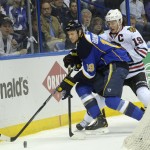 St. Louis Blues' Jay Bouwmeester, left, and Chicago Blackhawks' Jonathan Toews, right, battle for the puck during the first period in Game 2 of a first-round NHL hockey playoff series on Saturday, April 19, 2014, in St. Louis. (AP Photo/Bill Boyce)
