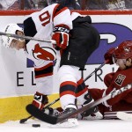 New Jersey Devils' Peter Harrold (10) tries to gain control of the puck as Arizona Coyotes' John Moore, right slides on the ice during the first period of an NHL hockey game Saturday, March 14, 2015, in Glendale, Ariz. (AP Photo/Ross D. Franklin)