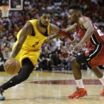 Cleveland Cavaliers guard Kyrie Irving (2) drives to the basket past Miami Heat guard Norris Cole during the second half of an NBA basketball game, Thursday, Dec. 25, 2014, in Miami. The Heat defeated the Cavaliers 101-91. (AP Photo/Lynne Sladky)