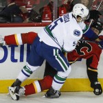Vancouver Canucks' Luca Sbisa, left, from Italy, takes out Calgary Flames' Brian Mcgrattan during first period NHL hockey action in Calgary, Alberta, Wednesday, Oct. 8, 2014. (AP Photo/The Canadian Press, Jeff McIntosh)