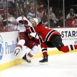 Phoenix Coyotes right wing David Moss, left, hits the board while competing for the puck with New Jersey Devils' Eric Gelinas during the first period of an NHL hockey game, Thursday, March 27, 2014, in Newark, N.J. (AP Photo/Julio Cortez)
