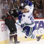 Vancouver Canucks' Shawn Matthias (27) gets tripped up by Arizona Coyotes' Michael Stone (26) during the first period of an NHL hockey game Thursday, March 5, 2015, in Glendale, Ariz. (AP Photo/Ross D. Franklin)
