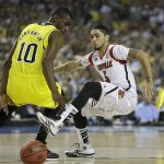 Louisville guard Peyton Siva (3) and Michigan guard Tim Hardaway Jr. (10) vie for a loose ball during the first half of the NCAA Final Four tournament college basketball championship game Monday, April 8, 2013, in Atlanta. (AP Photo/Charlie Neibergall)