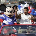 The 2014 Super Bowl MVP Malcolm Smith, right, a Seattle Seahawks linebacker, waves to spectators as he rides in a parade at Walt Disney World with Mickey Mouse, Monday, Feb. 3, 2014, in Lake Buena Vista, Fla. The Seahawks defeated the Denver Broncos 43-8 in Sunday's Super Bowl XLVIII NFL football game in East Rutherford, N.J. (AP Photo/John Raoux)