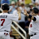 Minnesota Twins' Josh Willingham, right, high-fives teammate Joe Mauer after they scored along with Jamey Carroll off a double by Justin Morneau in the fourth inning of an exhibition spring training baseball game against the Pittsburgh Pirates, Monday, Feb. 25, 2013, Fort Myers, Fla. (AP Photo/David Goldman)