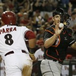 Arizona Diamondbacks' Gerardo Parra, left, heads back to the dugout after scoring a run as Miami Marlins' Jeff Mathis, right, calls for time during the fifth inning of a baseball game on Monday, June 17, 2013, in Phoenix. (AP Photo/Ross D. Franklin)