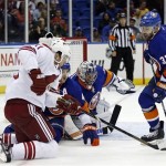 New York Islanders defenseman Andrew MacDonald, second from left, and Islanders goalie Evgeni Nabokov, second from right, of Kazakhstan, defend as Phoenix Coyotes center Martin Hanzal, left, of Czech Republic, tries to shoot in the third period of an NHL hockey game at Nassau Coliseum in Uniondale, N.Y., Tuesday, Oct. 8, 2013. The Islanders won Coyotes 6-1. New York Islanders defenseman Brian Strait (37) watches at right. (AP Photo/Kathy Willens)
