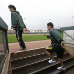 Oakland Athletics' Hiroyuki Nakajima runs out of the dugout with his interpreter Hiroo Nishi after reporting for the start of baseball spring training, Monday, Feb. 11, 2013, in Phoenix. (AP Photo/Darron Cummings)