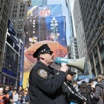 A New York City police officer use a bull horn to direct pedestrians visiting Super Bowl Boulevard Saturday Feb. 1, 2014 in New York. (AP Photo/Bebeto Matthews)