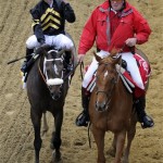 Jockey Gary Stevens, left, clenches his fist aboard Oxbow, as outrider Clark Kelly guides them to the winner's circle after winning the 138th Preakness Stakes horse race at Pimlico Race Course, Saturday, May 18, 2013, in Baltimore. (AP Photo/Nick Wass)
