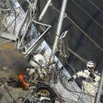 The engine from Kyle Larson's car sits burning next to other parts from the car near a grandstand fence after the car hit the wall and safety fence along the front stretch on the final lap of the NASCAR Nationwide Series auto race at Daytona International Speedway in Daytona Beach, Fla., Saturday, Feb. 23, 2013. (AP Photo/Phelan M. Ebenhack)
