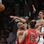 Brooklyn Nets center Brook Lopez, right, passes around the double-team of Chicago Bulls forward Carlos Boozer, left, and center Joakim Noah (13) in the second half of Game 5 of their first-round NBA basketball playoff series, Monday, April 29, 2013, in New York. The Nets won 110-91. (AP Photo/Kathy Willens)