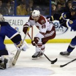 Phoenix Coyotes' Mikkel Boedker, of Denmark, handles the puck as St. Louis Blues goalie Jaroslav Halak, left, of Slovakia, and Jay Bouwmeester, right, defend during the first period of an NHL hockey game Tuesday, Jan. 14, 2014, in St. Louis. (AP Photo/Jeff Roberson)