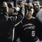 Colorado Rockies' Carlos Gonzalez (5) is congratulated by teammates after scoring on a Todd Helton RBI double against Arizona Diamondbacks relief pitcher Bryan Shaw during the eighth inning of a baseball game Friday, April 13, 2012, in Denver. (AP Photo/Jack Dempsey)