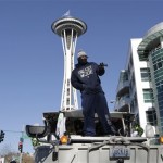 Seattle Seahawks' Marshawn Lynch stands on a military vehicle's hood during a parade for NFL football's Super Bowl XLVIII champions in Seattle, Wednesday, Feb. 5, 2014. The Seahawks defeated the Denver Broncos on Sunday. (AP Photo/John Froschauer)