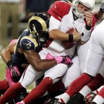 Arizona Cardinals quarterback Kevin Kolb, right, carries the ball as St. Louis Rams defensive end Robert Quinn tackles during the first quarter of an NFL football game, Thursday, Oct. 4, 2012, in St. Louis. (AP Photo/Tom Gannam)