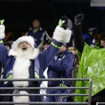 A Seattle Seahawks fan dressed as Santa celebrates a play against the New Orleans Saints during an NFL football game, Monday, Dec. 2, 2013, in Seattle. (AP Photo/Scott Eklund)