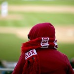 Boston Red Sox fan Bonnie Brewer, of Sarasota, Fla., sits bundled up in a scarf as a cold front passes through the area while watching the ninth inning of an exhibition spring training baseball game between the Red Sox and the New York Yankees, Sunday, March 3, 2013, in Fort Myers, Fla. (AP Photo/David Goldman)