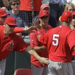 Los Angeles Angels' Albert Pujols is greeted by teammates after scoring during the first inning of a spring training baseball game against the Oakland Athletics Monday, March 5, 2012, in Phoenix. (AP Photo/Darron Cummings)