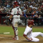 Arizona Diamondbacks' Cody Ross, right, slides in to score a run as Philadelphia Phillies' Carlos Ruiz watches the infield action at first base during the sixth inning of a baseball game on Thursday, May 9, 2013, in Phoenix. (AP Photo/Ross D. Franklin)