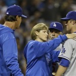 Los Angeles Dodgers pitcher Zack Greinke is attended to by the team trainer Sue Falsone as manager Don Mattingly, left, and coach Davey Lopes look on during an interlude of a brawl that started when Greinke hit San Diego Padres' Carlos Quentin with a pitch in the sixth inning of baseball game in San Diego, Thursday, April 11, 2013. The battle restarted moments later. (AP Photo/Lenny Ignelzi)