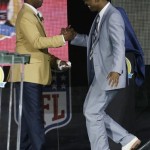 Former NFL football player Cris Carter, left, is greeted by his presenter, his son Duron, during the induction ceremony at the Pro Football Hall of Fame Saturday, Aug. 3, 2013, in Canton, Ohio. (AP Photo/Tony Dejak)
