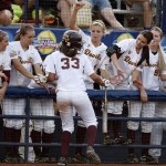 Arizona State's Alix Johnson, center slaps hands with her teammates as she runs along the dugout after scoring against Florida in the third inning of a Women's College World Series championship series game in Oklahoma City, Monday, June 6, 2011. (AP Photo/Sue Ogrocki)