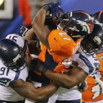 Denver Broncos running back Knowshon Moreno (27) is tackled by Seattle Seahawks defensive end Chris Clemons (91) and defensive end Cliff Avril (56) during the first half of the NFL Super Bowl XLVIII football game Sunday, Feb. 2, 2014, in East Rutherford, N.J. (AP Photo/Matt York)