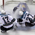 St. Louis Blues goalie Jaroslav Halak, top, of Slovakia, is sprayed by San Jose Sharks' Torrey Mitchell (17) and T.J. Galiardi (37) while stopping a puck during the second period of Game 1 of an NHL hockey first-round playoff series on Thursday, April 12, 2012, in St. Louis. (AP Photo/Jeff Roberson)
