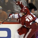 Phoenix Coyotes left-winger Shane Doan, front, battles New York Rangers defenseman Ryan McDonagh, rear, for a loose puck in the second period of an NHL hockey game Saturday, Dec. 17, 2011 in Glendale, Ariz. (AP Photo/Paul Connors)