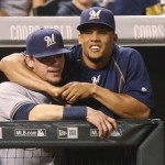               Milwaukee Brewers' Carlos Gomez, right, jokes with second baseman Scooter Gennett as they lean over the dugout rail to watch the Colorado Rockies in the seventh inning of a baseball game Friday, June 19, 2015, in Denver. Milwaukee won 9-5. (AP Photo/David Zalubowski)
            
